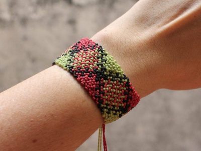 Pulsera ancha de macramé tejida a mano con nudos formando patrón escocés